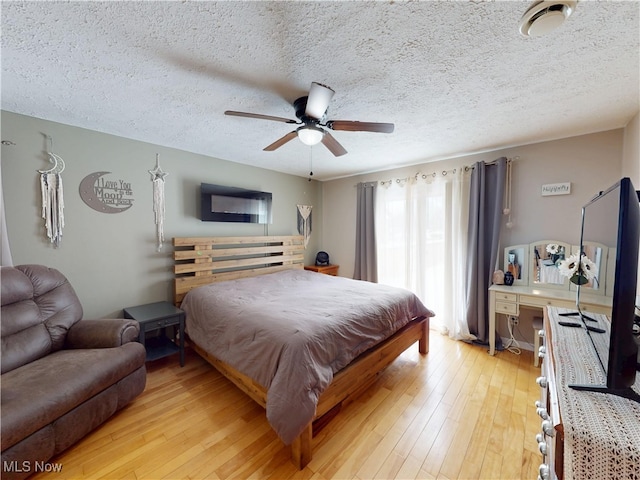 bedroom with ceiling fan, a textured ceiling, and light wood finished floors