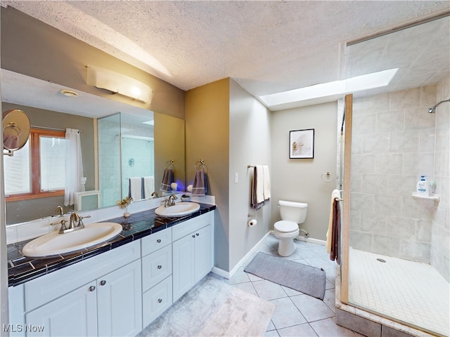 full bathroom featuring a stall shower, a textured ceiling, a sink, and tile patterned floors