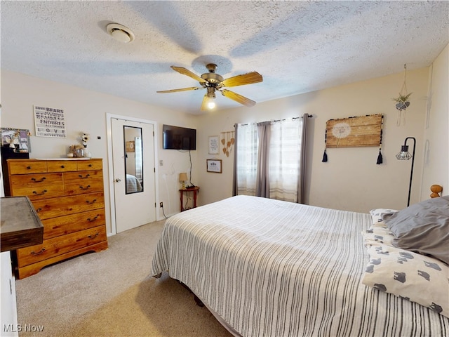 bedroom featuring ceiling fan, a textured ceiling, and light colored carpet