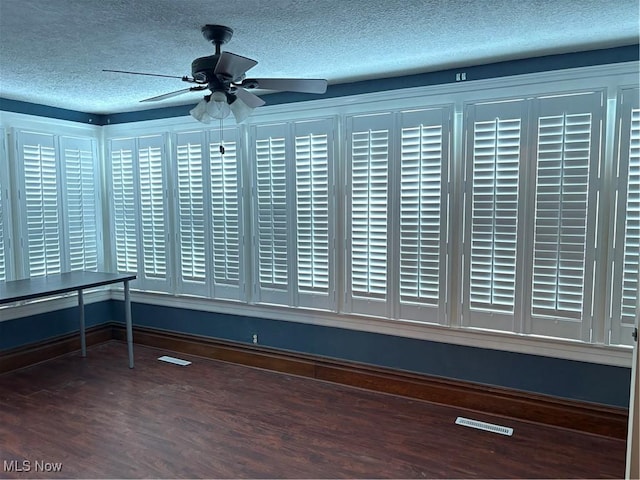 interior space with ceiling fan, visible vents, dark wood finished floors, and a textured ceiling