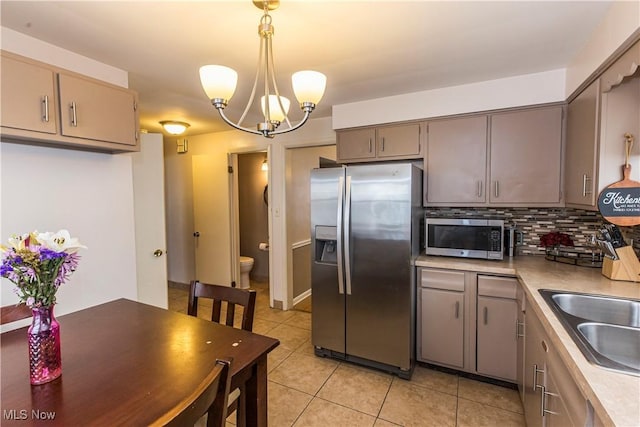 kitchen featuring light tile patterned floors, tasteful backsplash, appliances with stainless steel finishes, hanging light fixtures, and light countertops