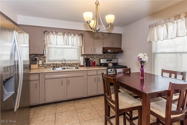 kitchen with range hood, decorative light fixtures, stainless steel appliances, light countertops, and a sink