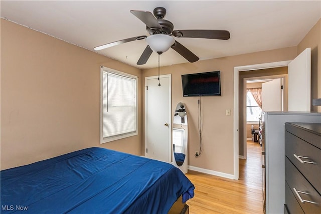 bedroom with baseboards, ceiling fan, and light wood-style floors