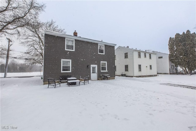 snow covered back of property with a chimney