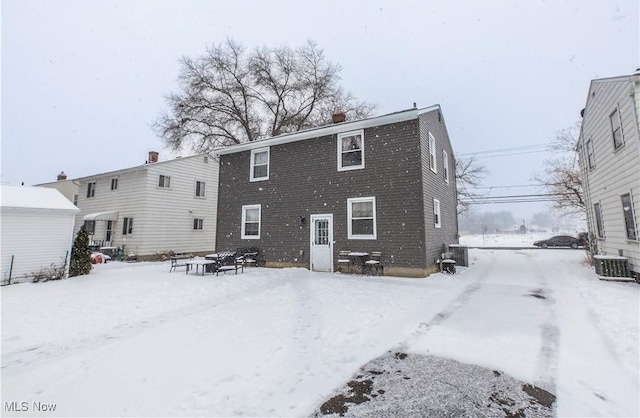 snow covered house with a chimney and central air condition unit