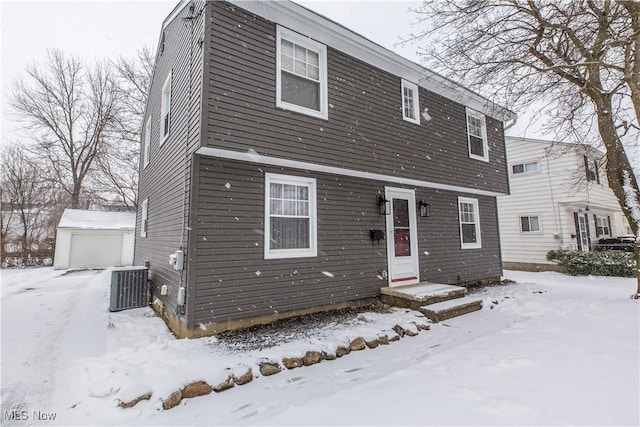 view of front of house with a garage, central AC, and an outbuilding