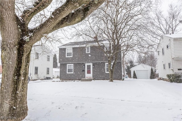 view of front of property with a garage, a chimney, a gambrel roof, and an outbuilding