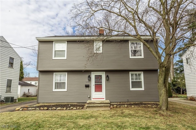 colonial house with a chimney, a front lawn, and central AC unit