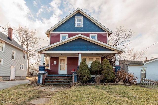 american foursquare style home featuring a porch and a front yard