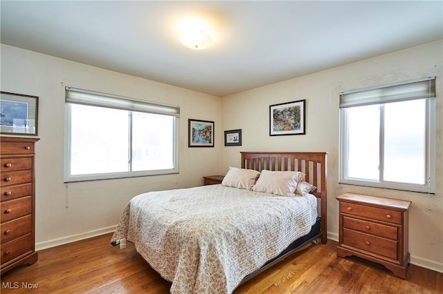 bedroom featuring multiple windows, baseboards, and wood finished floors