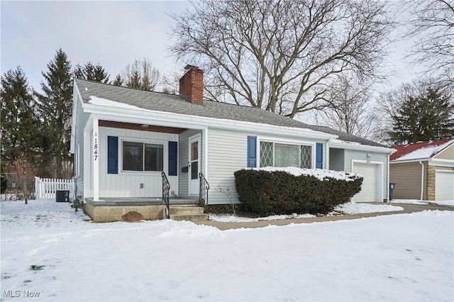 view of front of house with roof with shingles, a chimney, an attached garage, central AC, and fence