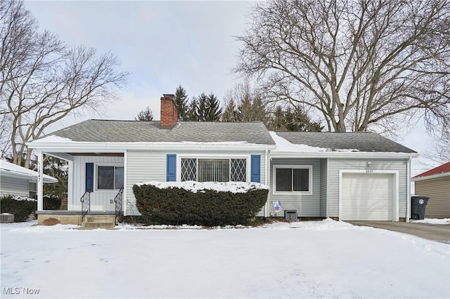 single story home with a garage, a shingled roof, a chimney, and board and batten siding