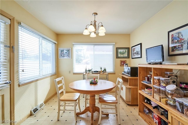 dining space featuring a chandelier, light floors, visible vents, and baseboards