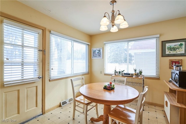 dining area with baseboards, visible vents, a notable chandelier, and light floors