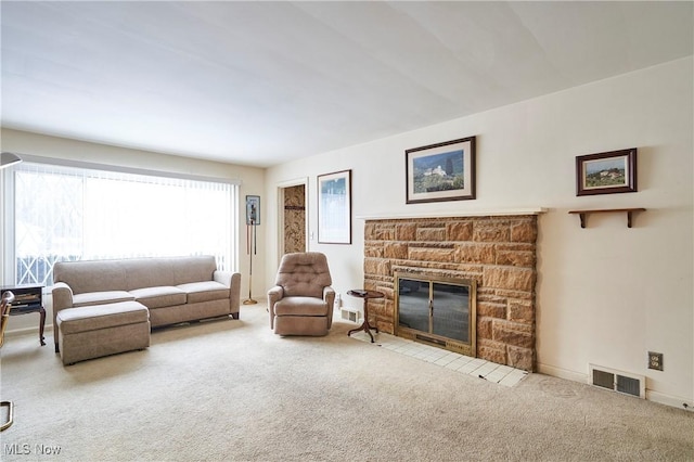 carpeted living area featuring baseboards, visible vents, and a stone fireplace