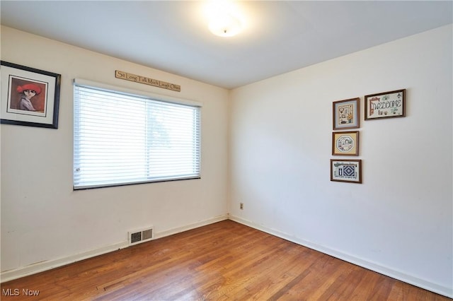 empty room with visible vents, baseboards, and wood finished floors