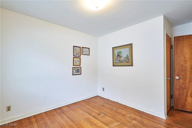 unfurnished room with baseboards and wood finished floors