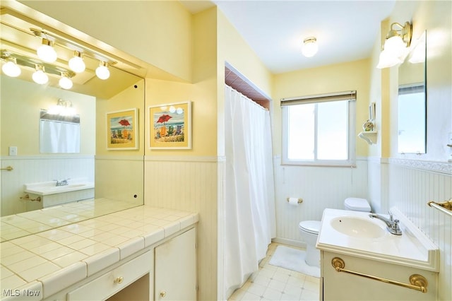 bathroom with a wainscoted wall, vanity, toilet, and tile patterned floors