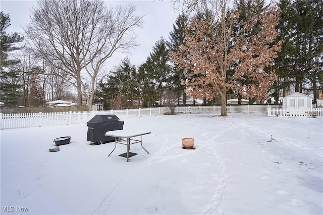 yard layered in snow featuring a storage unit, an outdoor structure, and a fenced backyard