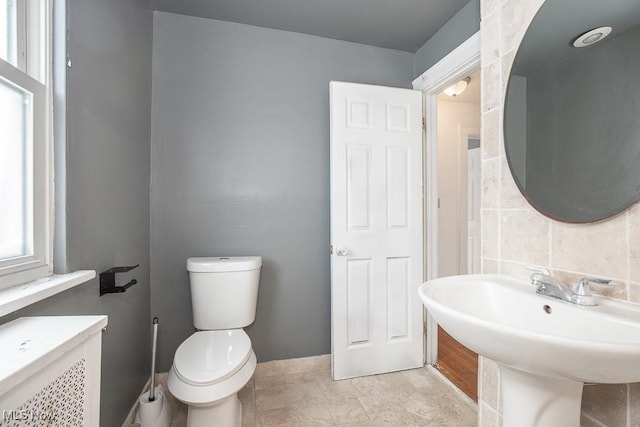 half bathroom with radiator, toilet, and a sink