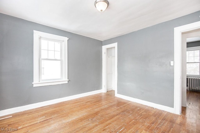 spare room featuring light wood-style floors, radiator heating unit, and baseboards