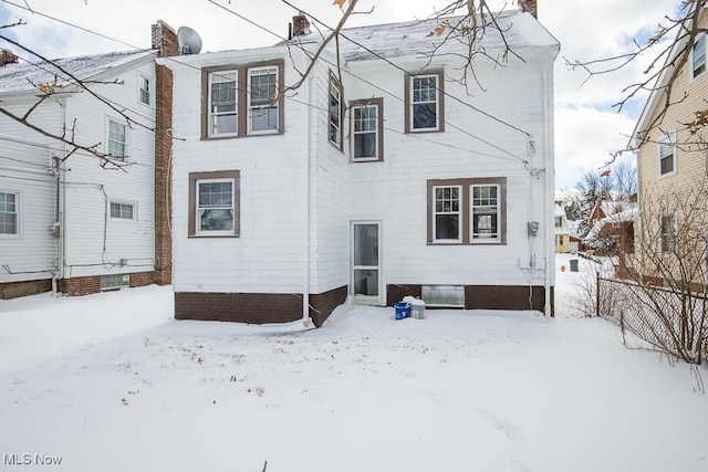 snow covered back of property featuring a chimney