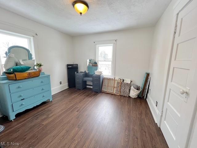 misc room with dark wood-style flooring, a textured ceiling, and baseboards