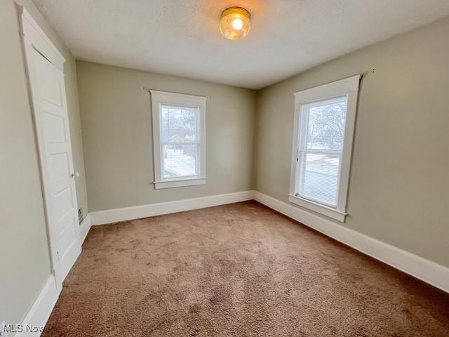 carpeted empty room featuring baseboards and a textured ceiling