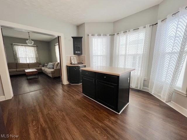 kitchen featuring a kitchen island, dark wood-style flooring, light countertops, and dark cabinetry