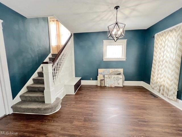 interior space with a notable chandelier, stairway, dark wood finished floors, and baseboards