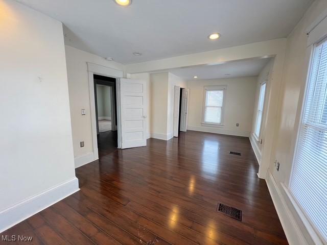 empty room featuring baseboards, visible vents, dark wood-style flooring, and recessed lighting