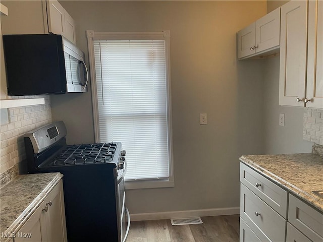 kitchen featuring white cabinetry, visible vents, appliances with stainless steel finishes, and decorative backsplash