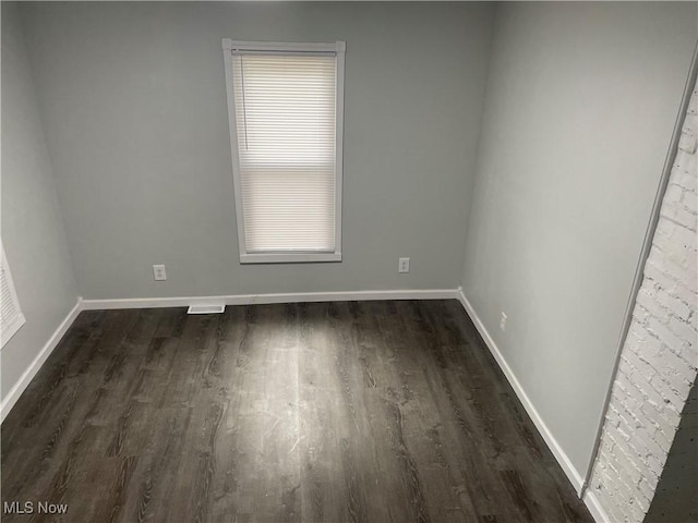 spare room featuring dark wood-style flooring and baseboards