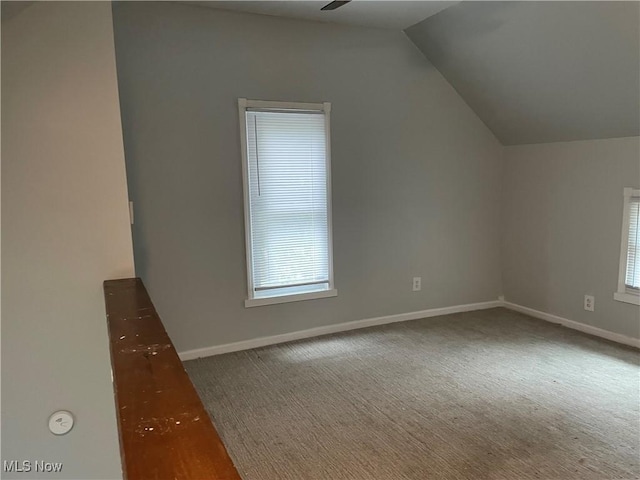 bonus room with a ceiling fan, dark colored carpet, vaulted ceiling, and baseboards