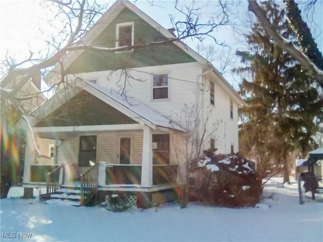 snow covered property with covered porch