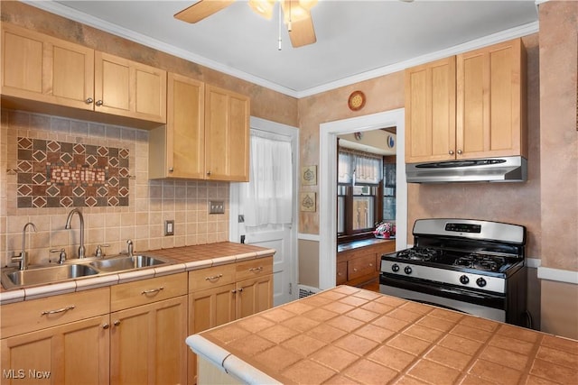 kitchen featuring a sink, under cabinet range hood, tile counters, and stainless steel range with gas stovetop