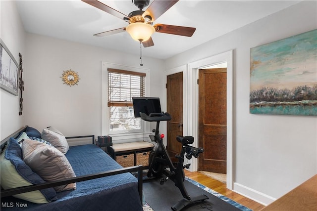 workout room featuring wood finished floors, a ceiling fan, and baseboards