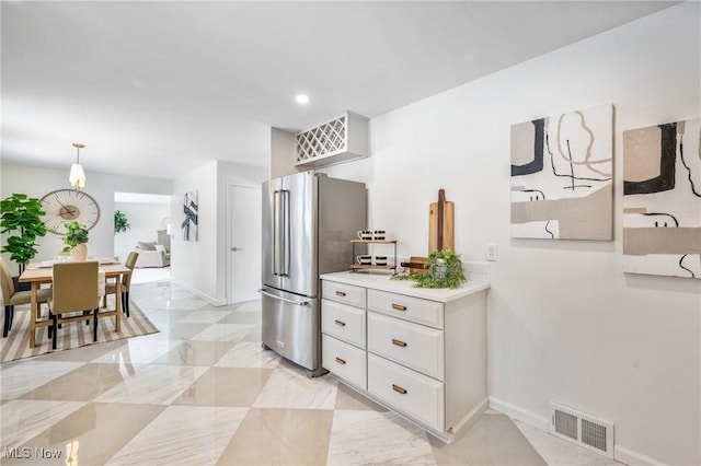 kitchen with high end refrigerator, visible vents, hanging light fixtures, light countertops, and white cabinetry