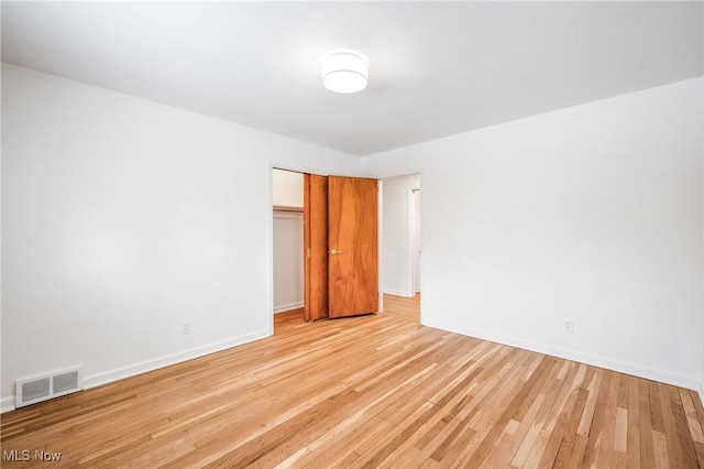 empty room featuring visible vents, light wood-style flooring, and baseboards