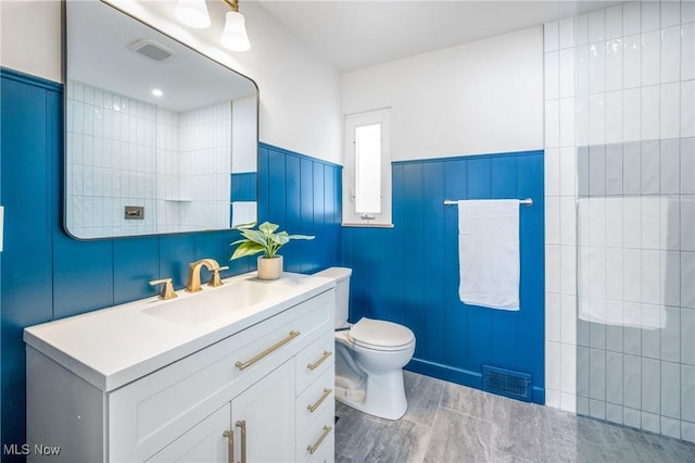 full bath with toilet, wainscoting, vanity, and visible vents