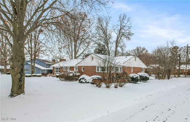 view of front of property featuring a garage, brick siding, and a chimney