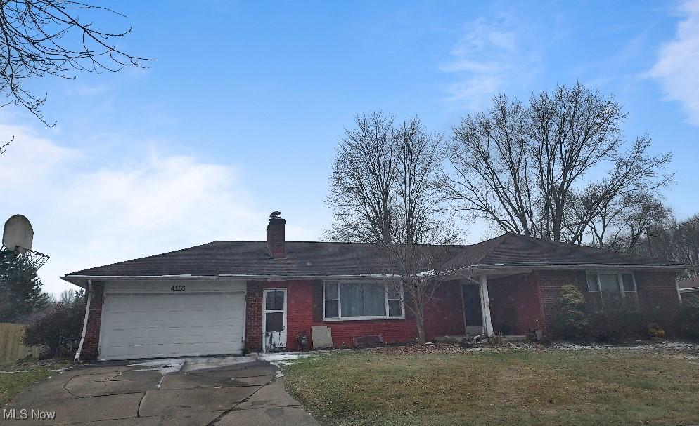 ranch-style house with an attached garage, brick siding, concrete driveway, a front lawn, and a chimney