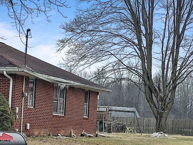 view of property exterior with a yard, brick siding, and fence