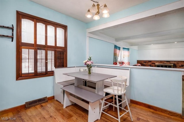 dining space with light wood-style flooring, beam ceiling, visible vents, and a notable chandelier