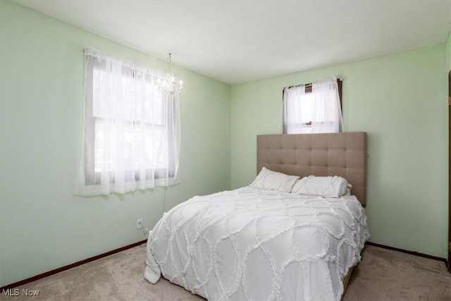 bedroom featuring light carpet, a chandelier, and baseboards