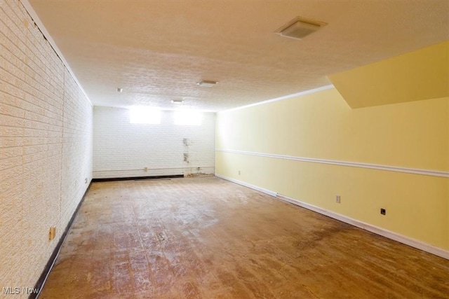 spare room featuring baseboards, visible vents, and brick wall