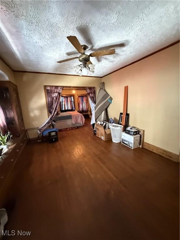 interior space featuring crown molding, ceiling fan, a textured ceiling, wood finished floors, and baseboards