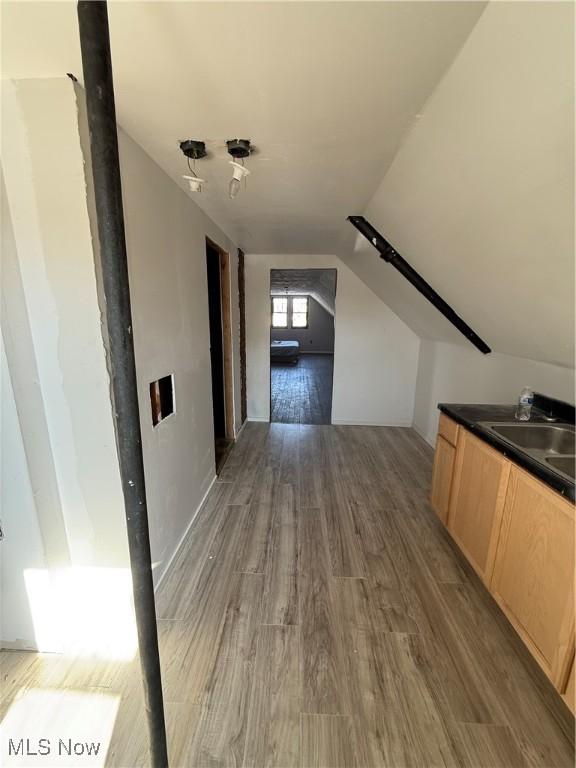 hallway with vaulted ceiling, dark wood-style flooring, and a sink