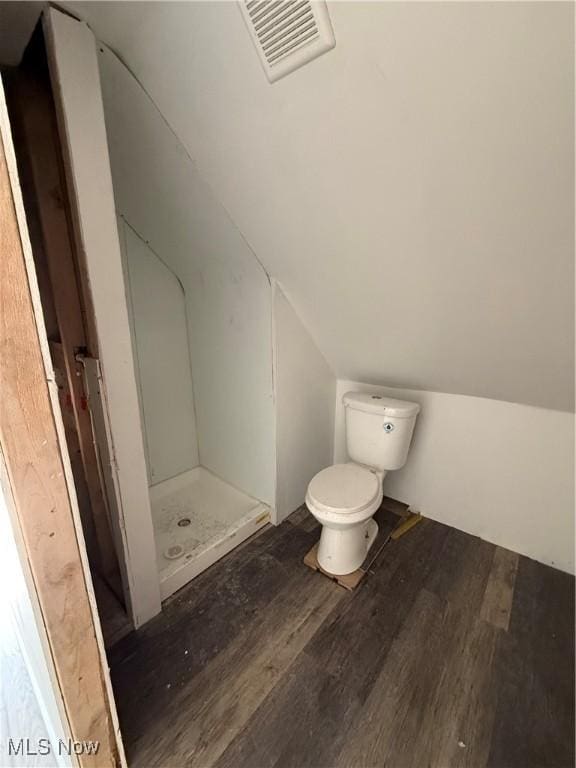 full bath featuring toilet, wood finished floors, visible vents, vaulted ceiling, and a shower stall