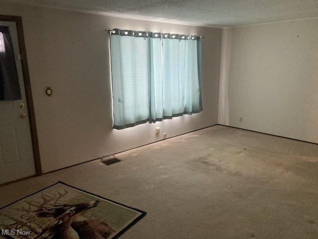 spare room featuring a textured ceiling, visible vents, and crown molding